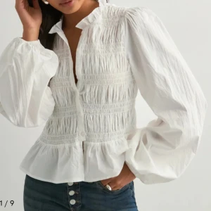 Vit blus med volanger från Nelly - Supersöt vit blus med volangkant nertill och puffiga långärmar. Knabbast andvänd därav säljer nu vidare. 🩷🩷 (säljer inte under 275kr) fraktar direkt 