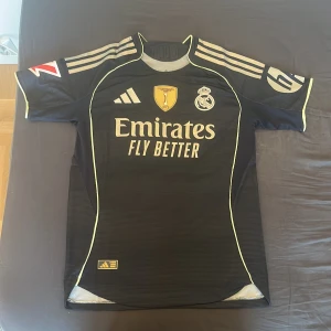 Real Madrid bortaställ Mbappe #10 - Real Madrid bortaställ 25/26. Svart/mörkblå med textur och mönster. Perfekt för att ha i skolan och på sommaren. 