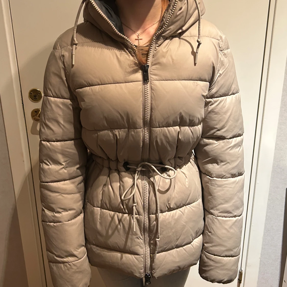 Beige pufferjacka med huva och snörning