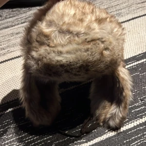 Brun pälsmössa med öronlappar - fräsch pälsmössa, riktigt mysig o varm t vintern typ🙏❤️‍🩹används ej, inte mkt o säga om denna. Pm vid intresse.
