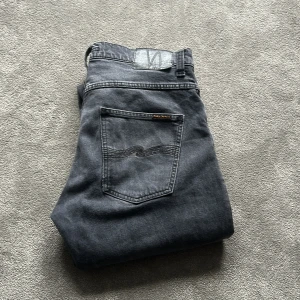  Nudie Jeans Grim Tim - Säljer ett par Nudie Jeans Grim Tim dark cove, modellen har klassisk femficksdesign och snygga broderade bakfickor. Materialet är 99% bomull och 1% elastan för lite stretch. Passformen är rak och normal, perfekt för dig som gillar stilrena jeans.