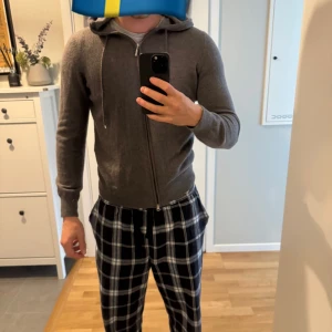 Grå hoodie i kashmir från Gran Sasso - Mjuk och lyxig grå hoodie från Gran Sasso i kashmir. Tröjan har dragkedja framtill, huva med snörning och ribbade muddar. Perfekt för dig som vill ha en stilren och bekväm look med premiumkänsla. Passar de som bär S/M.