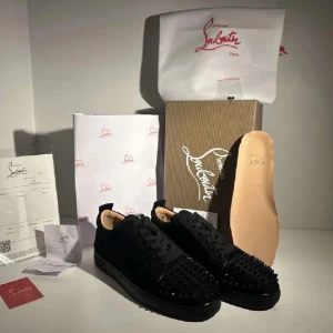 Christian Louboutin svarta sneakers med nitar - Svarta sneakers från Christian Louboutin med ikonisk röd sula och svarta nitar på tån. Skorna har snörning, rund tå och platt sula. Tillverkade i skinn och mocka med lyxig känsla och edgy vibe. Hör av dig om frågor ? Kan gå ner pris 