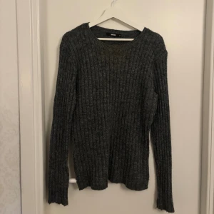 Mörkgrå ribbad stickad tröja Bik Bok - Mysig mörkgrå stickad tröja från Bik Bok med ribbad struktur. Tröjan har rund halsringning och långa ärmar, perfekt för kyliga dagar. Enkel och stilren modell som är lätt att matcha med olika outfits.