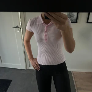 Rosa ribbad polotopp från Zara - Säljer en ljusrosa ribbad polotopp från Zara med korta ärmar och klassisk krage. Storlek S och bra skick.