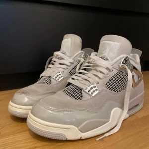 Nike Air Jordan 4 frozen moments - (skolådan ingår ej!!!)Säljer ett par Nike Air Jordan 4 i snygg grå färg med detaljer i mocka och mesh. Skorna har vita och silverfärgade accenter, klassisk snörning och den ikoniska Jumpman-loggan på hälen. Perfekta för dig som gillar stilrena och exklusiva sneakers.