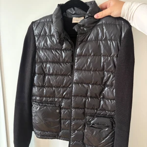 Svart jacka från Moncler - Svart pufferjacka från Moncler med glansig quiltad front och två fickor med lock. Passar både XS och S, mycket stretch baktill.                  Ordinarie pris: 9500