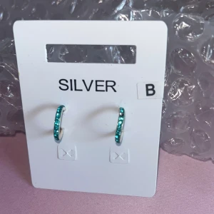 Silverörhängen med blå stenar - Små hoops örhängen. Ena örhänget (höger på bilden) saknar en liten sten vilket syns på första bilden. 