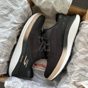 Svarta Skechers Arch Fit sneakers - Snygga svarta Skechers Arch Fit sneakers helt nya kvar i lådan endast testade. Skorna har snörning, bekväm, stötdämpande sula med Arch Fit-teknologi. Perfekta för dig som vill ha både stil och komfort till vardags eller träning. Storlek 39 vilket jag vanligtvis har men stora i storlek därför jag säljer, mer storlek 40❤️ köpta för 1500kr