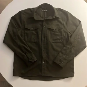 J.Lindeberg Mörkgrön Overshirt storlek M - Skön overshirt som passar bra för dig som vill ha en lite mer avslappnad overshirt för dina plagg på plagg outfits. Använd nästintill ingenting, säljer för den är lite stor för mig då jag är en S