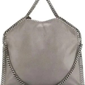 Grå axelväska från Stella McCartney - Snygg grå axelväska från Stella McCartney i mjuk mocka med kraftiga silverfärgade kedjor längs kanterna och som axelrem. Väskan har en cool, modern look och rundad form, perfekt för dig som vill sticka ut med en statementväska.