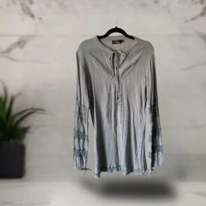 Grå blus med knyt och spetsdetaljer - Supersnygg grå blus från Days med långa ärmar och dekorativa spetsdetaljer på ärmarna. Blusen har knytning vid halsen och lätt skrynklat tyg som ger en avslappnad vibe. Perfekt för dig som gillar boho-stil och unika detaljer.