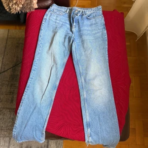 Ljusblå raka jeans  - Ljusblå jeans med klassisk femficksdesign och raka ben. Jeansen har normalhög midja, subtilt sliten tvätt, små slit på botten av jeansen, och litet hål på bakfickan. 