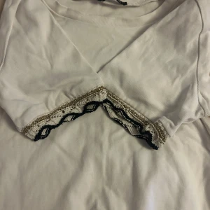 Vit topp med spetsdetalj från Zara - vit stickad stretchig, kortärmad tröja från zara med guldsvart detalj vid ärmarna! 🫶🏼!!!väljs postnord när du beställer inte instabox!!!