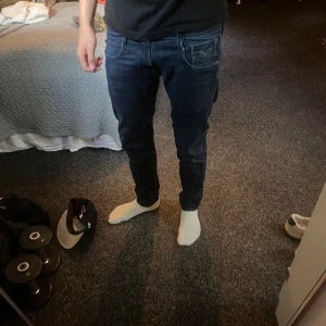 Replay Anbass slim fit jeans blå - Snygga mörkblå Replay Anbass jeans i slim fit-modell. Klassisk femficksdesign, normal midja och smal passform hela vägen ner. Jeansen är gjorda i stretchigt denim för extra komfort och har diskreta slitningar för en modern look.