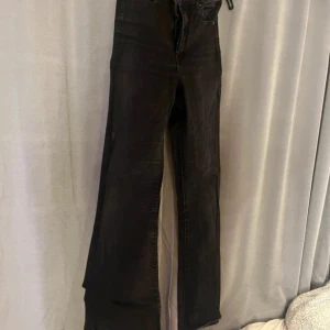 Svarta bootcut jeans med slits - Svarta jeans med bootcut passform och slits nertill på benen. Klassisk femficksmodell med hög midja och raka bakfickor. Jeansen har en lätt tvättad look och är tillverkade i jeansmaterial.