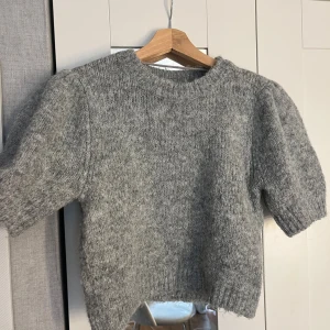 Grå stickad tröja från Vero Moda - Mysig grå stickad tröja från Vero Moda med korta ärmar, tröjan är knappt använd. Kan sänka priset, vill bli av med kläder.