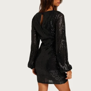 Svart glittrig kortklänning från Nelly - Supersnygg svart kortklänning från Nelly med glittriga paljetter över hela klänningen. Den har långa puffiga ärmar och rund halsringning. Perfekt för dig som vill sticka ut och glänsa! Perfekt att ha på nyår! Säljer denna kläning då den aldrig kommer till användning.