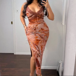 Brun mönstrad långklänning med slits - Säljer en snygg långklänning i bruna och beige toner med leopard- och paisleymönster. Klänningen har smala axelband, v-ringning med spetsdetalj och en hög slits på sidan. Figurnära passform och mjukt, stretchigt material som sitter perfekt.