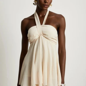 Champagnefärgad halterneckklänning Miss Rosier - Supersöt kort klänning i champagnefärg från Miss Rosier. Halterneck-modell med omlott-detalj framtill och lätt, flowy tyg som ger en luftig känsla. .Använd 1 gång. Nypris 700 