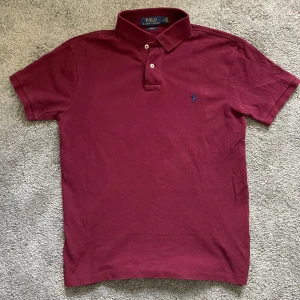 Vinröd pikétröja från Polo Ralph Lauren M - Snygg vinröd pikétröja från Polo Ralph Lauren i slim fit. Klassisk krage, två knappar och broderad blå logga på bröstet. Tillverkad i bomull och har korta ärmar. Perfekt för en clean och stilren look. 😎OBS Alla brudar kommer bli galna i dig😎
