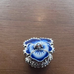 Berlock till Pandora armband - Blå blomberlock i silver till Pandora armband. Så gott som nytt. Använt färre än 10 gånger. (Armband ingår ej i priset)