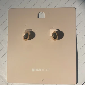 Guldiga örhängen från Gina Tricot - Snygga droppformade örhängen i guldig färg från Gina Tricot. De har en modern, blank yta och är tillverkade av återvunnen zinklegering. Perfekta för att ge din look en stilren touch.