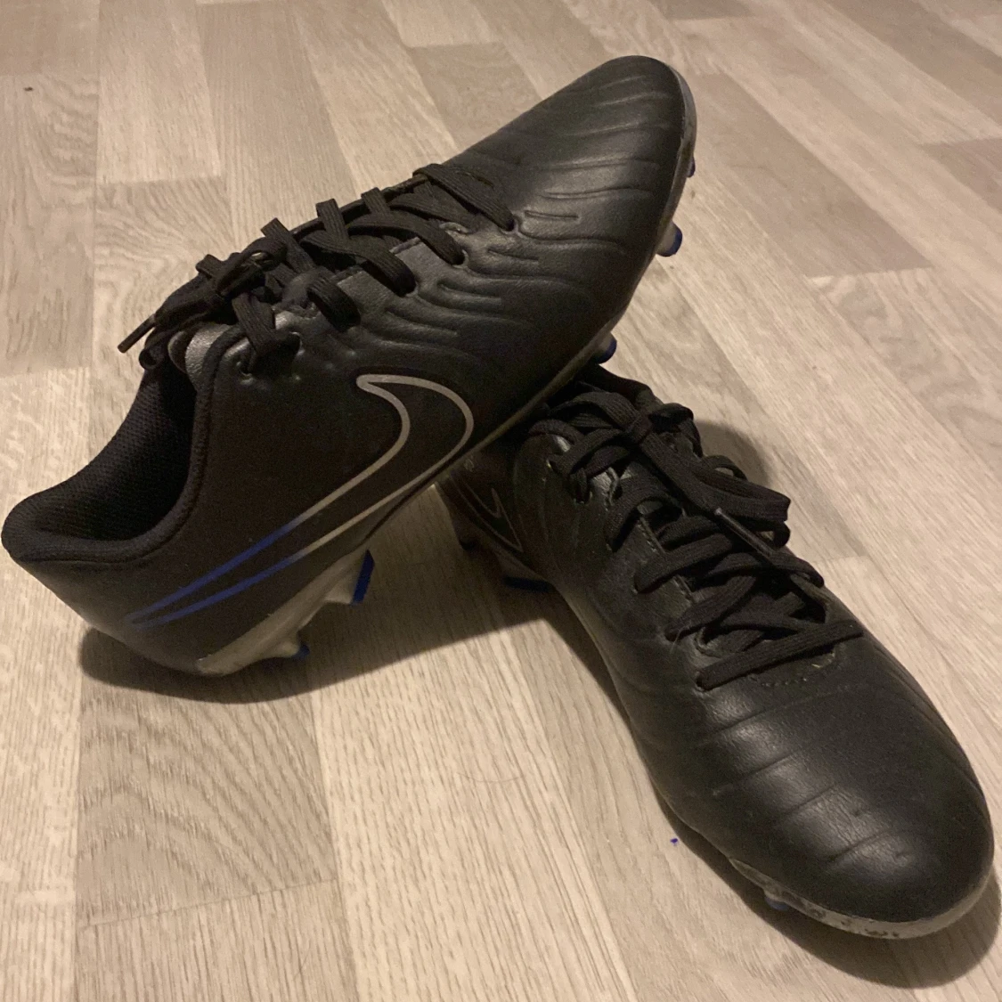 Svarta Nike fotbollsskor med blå detaljer