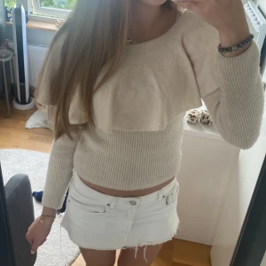 Beige stickad tröja med volang H&M - Superfin beige stickad tröja från H&M med bred volang över axlarna och ribbad midja. Tröjan är croppad och har långa ärmar, perfekt för dig som gillar en söt och trendig look. Passar till både jeans och kjol.🥰💞😇