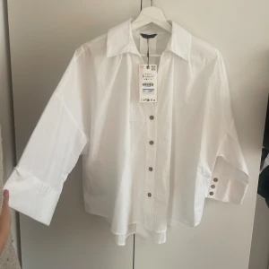 Vit ”oversized” viral skjorta med vid vida ärmar Zara - Viral trendig skjorta. Jättefin men inte riktigt min stil. Prislapp är kvar och den är endast provad. (Kan dock finnas pytte lite puder vid kragen från provning, går bort i tvätten)