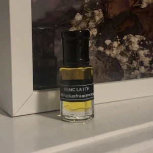 Bianc Latte parfymolja Nablusfragrances - Säljer en liten flaska parfymolja från Nablusfragrances med doften Bianc Latte. Flaskan är genomskinlig med svart lock och etikett, och innehållet är ljusgult. Perfekt storlek att ha med sig i väskan.