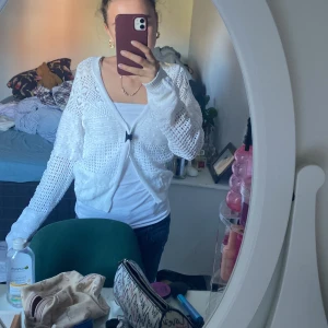 Vit stickad kofta - Säljer en vit stickad kofta från C i storlek XS. Koftan har ett öppet hålmönster, långa ärmar och knyt framtill. Den är lätt och luftig, perfekt för lager-på-lager och har en söt, feminin vibe. Passar dig som gillar en chill och stilren look.