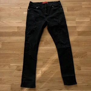 Svarta skinny jeans från Levis - Svarta skinny jeans från Levis med slitna detaljer på framsidan. Klassisk femficksmodell med dragkedja och knapp. Jeansen har en smal passform och är tillverkade i stretchigt denim för extra komfort.