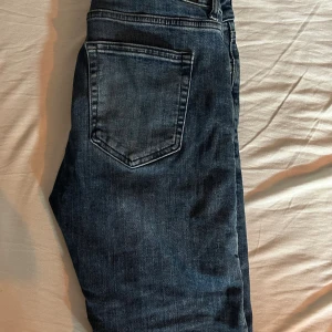 Lite mörkblåa slim jeans - Schyssta jeans från dressman som har en liten slitning. Slim fit och är storlek 30. Har använt dom några gånger bara!