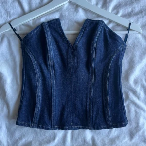 Mörkblå jeanskorsett med v-ringning - Säljer en snygg mörkblå korsettopp i jeansmaterial med v-ringad hals, i storlek XS😊