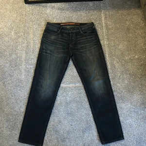 Mörkblå Jack & Jones jeans (Tapered fit) - Snygga mörkblå jeans från Jack & Jones. Nyköpta, endast använda en gång. Jag säljer dessa då dem är lite stora i midjan på mig. Jeansen är i Tapered fit och har storleken W32 & L32