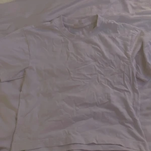 Vit t-shirt från Gina Tricot - En basic vit t-shirt från Gina Tricot, basically basics-kollektionen. T-shirten har rund halsringning och korta ärmar. Perfekt för en clean och enkel look, lätt att matcha med allt. Materialet är mjuk bomull.