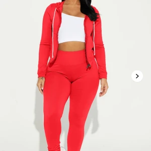 Röd hoodie med vita ränder - Röd hoodie med huva och dragkedja framtill. Långa ärmar med två vita ränder längs sidorna för en sportig look. Justerbar huva med vita snören och ribbad nederkant. Perfekt för en avslappnad stil.