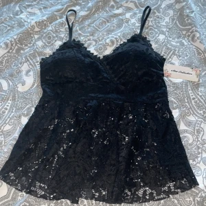 Svart spetslinne från New Collection - Supersnygg svart linnetopp med tunna axelband och v-ringad spetskant. Toppen är helt täckt av spets med blommigt mönster och har en lätt utsvängd passform. Köpte den på en marknad för 300kr i somras, ångrade mig och ville ha mörkblå istället men de var försent att byta🥲 den är endast testat!🤍