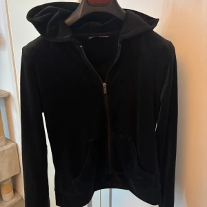 Svart velour hoodie med dragkedja - Mjuk och skön svart hoodie i velour med dragkedja framtill och två fickor. Band fattas