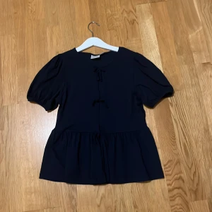 Mörkblå blus med puffärm - Supersöt mörkblå blus från Gina Tricot med puffiga korta ärmar och volang nedtill. Har används 2 gånger, säljer då den har blivit för liten. 