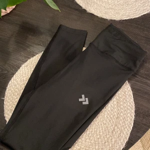 Svarta leggings från lager157 med snörning - Svarta leggings från 157 med hög midja och snörning i midjan, storlek S. Tillverkade i stretchigt material med quickdry-teknologi, perfekta för träning. Materialet är 90% polyester och 10% elastan för en tight och bekväm passform.