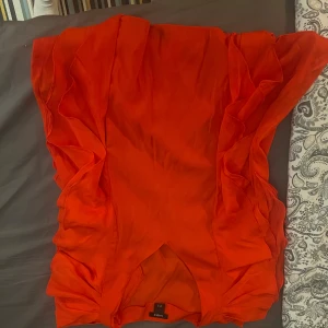 Röd volangblus från Lindex XS - Snygg röd blus från Lindex i storlek XS. Blusen har volangdetaljer längs sidorna och är tillverkad i ett lätt, flowy material som ger en cool look. Perfekt för dig som vill sticka ut med färg och stil.