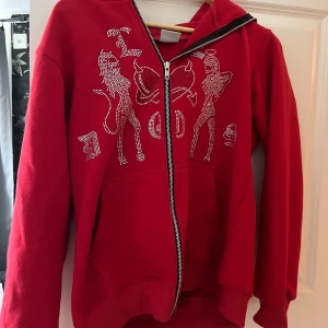 Röd hoodie med strass från Le Dos - Cool röd hoodie från Le Dos med blänkande strassmotiv framtill och hel dragkedja som går hela vägen upp i huvan. 