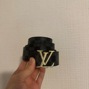 svart rutigt skärp - Stilrent svart bälte med guldig badge i storlek 110 