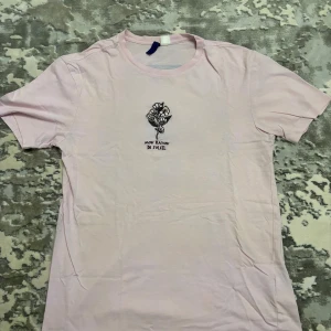 Ljusrosa t-shirt med broderi och tryck - Ljusrosa t-shirt med korta ärmar och rund hals. Framsidan har ett broderat blommotiv och texten 'Mon Rayon De Soleil'. Baksidan har ett stort tryck med körsbärsblommor och blå himmel. Skön och mjuk bomull, perfekt för en chill look.