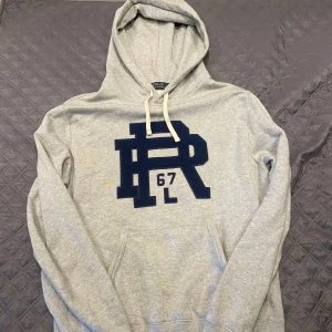 Ralph Lauren Hoodie - Grå hoodie från Ralph Lauren med blått tryck på framsidan. Hör gärna av dig vid funderingar:)