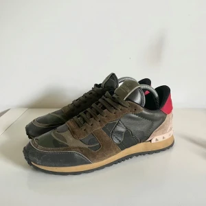 Valentino Rockrunner sneakers camouflage - Galet feta Valentino Garavani Rockrunner sneakers i mycket bra skick med camouflage-mönster i grönt, brunt och svart till ett otroligt pris av bara 1699. Storlek 41. Tveka inte på att fråga om du undrar något!
