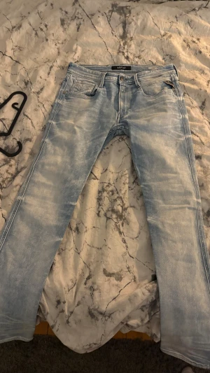 Replay Anbass ljusblå jeans, stl 31 - Säljer ett par Replay Anbass jeans i ljusblå tvätt med snygga slitningar. Modellen har klassisk femficksdesign, smal passform och normal midja. Materialet är mjukt jeans-tyg och bakfickorna har Replay-logga. Perfekt för dig som gillar en fräsch och modern look.size 31 och längd 32.skriv gärna vid frågor.pris kan diskuteras.