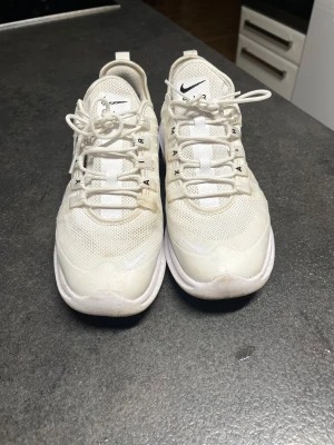 Nike Air Max vita sneakers - Säljer ett par fräscha Nike Air Max sneakers i helvitt med mesh-överdel och snygga detaljer. Skorna har snörning, platt sula och synlig Air Max-dämpning i hälen. Perfekt för dig som gillar stilrena och sportiga sneakers med skön komfort. Lite smutsiga men går att få bort. Priset kan diskuteras